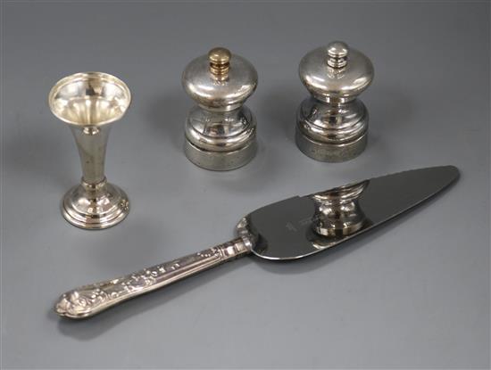 A pair of modern silver mounted salt and pepper mills, a small vase and a cake slice.